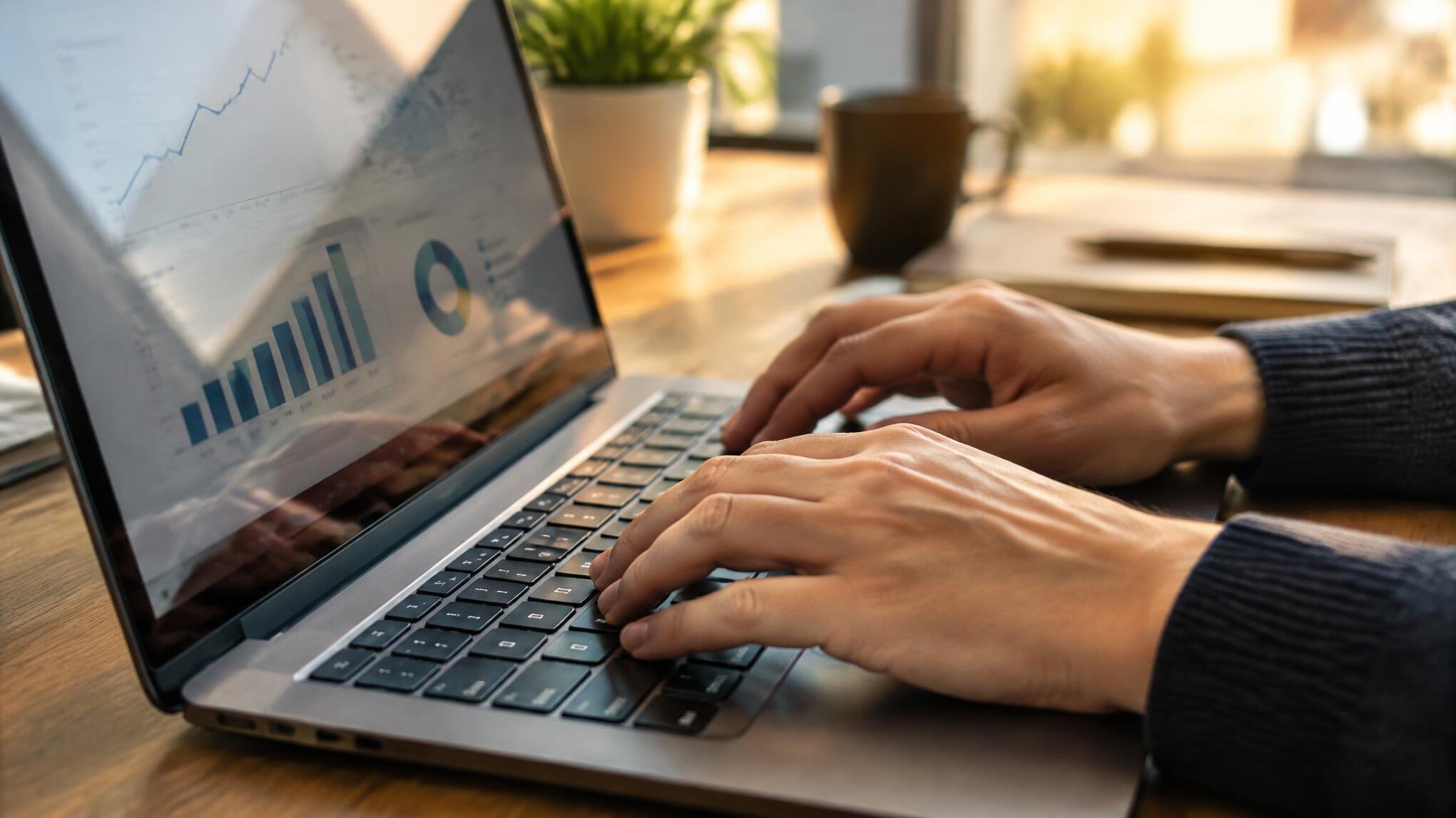 Close-up of hands typing on a laptop with an analytics chart visible
